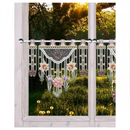 Ein Spitzenvorhang mit detaillierten Schmetterlings- und Blumenmustern bedeckt ein Fenster mit einem hellen Holzrahmen. Das Sonnenlicht fällt durch die Bäume draußen und beleuchtet eine mit gelben Wildblumen übersäte Wiese.