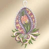 Ein gesticktes Ornament in Form eines Eies zeigt in der Mitte eine rosa Tulpe mit grünen Blättern. Der Hintergrund ist mit gelben und violetten Blumenmustern versehen und der Rand ist mit weißer Spitze eingefasst. Ein mehrfarbiges Band und Grünzeug akzentuieren den Sockel.