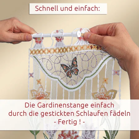 Zwei Hände führen eine Stange durch die bestickten Schlaufen am oberen Ende eines dekorativen Vorhangs mit Schmetterlings- und Blumenmustern. Der deutsche Text gibt Anweisungen zum Aufhängen des Vorhangs, indem die Stange durch die Schlaufen geführt wird.