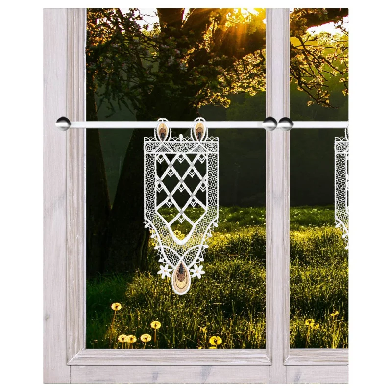 An einem Fenster hängt ein Dekor aus weißer Spitze, wobei die untere Hälfte mit verschlungenen Spitzenmustern versehen ist. Durch das Fenster sind eine grüne Wiese mit Löwenzahn und ein großer Baum zu sehen, der vom Sonnenlicht, das durch die Äste des Baumes fällt, beleuchtet wird.