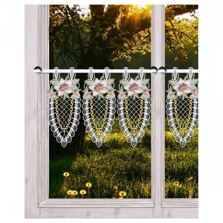 Nahaufnahme eines Fensters mit einem hellen Holzrahmen und Spitzenvorhängen mit Blumenmustern. Außerhalb des Fensters befindet sich eine beleuchtete Szene mit grünem Gras, Löwenzahn und Bäumen. Das Sonnenlicht fällt durch die Äste der Bäume auf den Rasen.