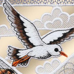 Ein bestickter Aufnäher zeigt einen weißen Vogel mit schwarzen und orangefarbenen Akzenten, der vor stilisierten weißen Wolken auf goldenem Hintergrund fliegt. Der Aufnäher weist fein gearbeitete Stickdetails auf, und im Himmelbereich ist eine Netzstruktur zu erkennen.