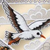 Ein bestickter Aufnäher zeigt einen weißen Vogel mit schwarzen und orangefarbenen Akzenten, der vor stilisierten weißen Wolken auf goldenem Hintergrund fliegt. Der Aufnäher weist fein gearbeitete Stickdetails auf, und im Himmelbereich ist eine Netzstruktur zu erkennen.